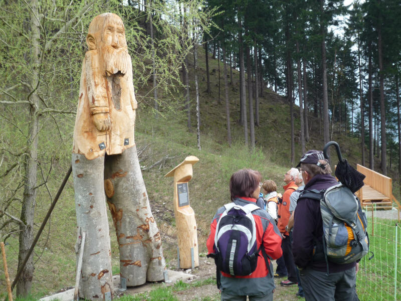 Wanderer bestaunen die Holzskulptur "Der Weidmann"